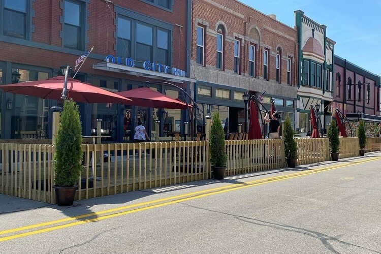 Gates, umbrella-covered tables, and potted plants give the streets a festive feel.