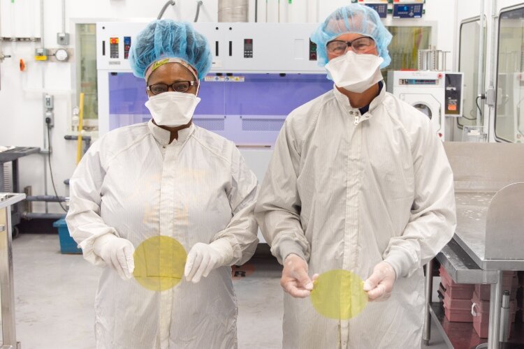 SK Siltron CSS employees Rose Dugan, left, and Kevin Moeggenborg hold 6-inch wide silicon carbide wafers the company manufactures in Bay County. The wafers are used to make semiconductor chips for electric vehicles. 