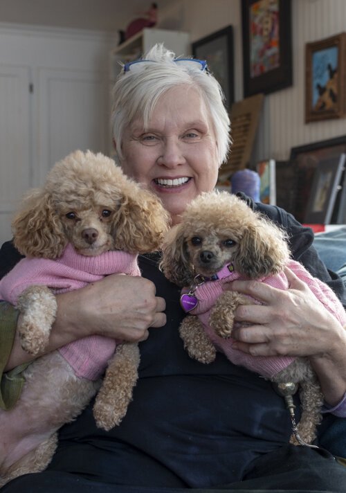 Sue Bergeson, who has discovered a new passion through Mid Michigan College’s lifelong learning program, sits in her living room holding her two dogs, Andromeda and Alsyon. 