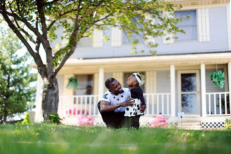 Otis Ebulela plays with his 17-month-old niece, Rebecca, in front of his Delta Township home-Photo Jena McShane