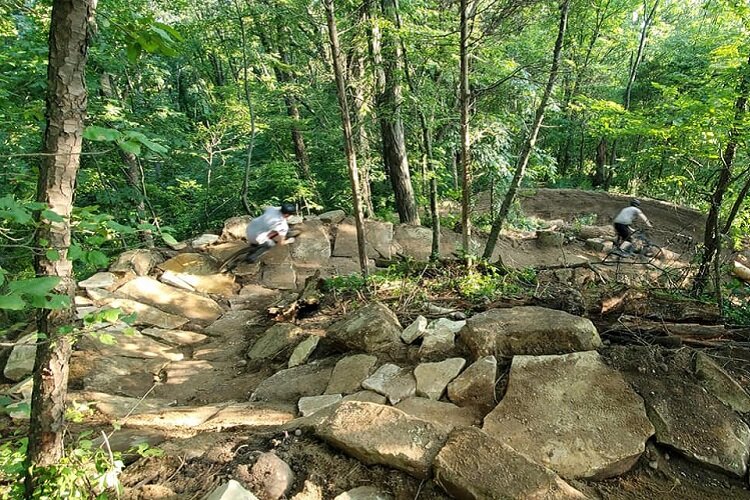 Bikers traverse a rocky stair at DTE Trail.