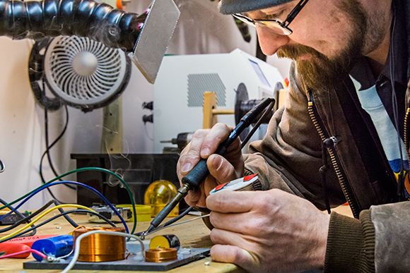 Wolfie Geske soldering a circuit board at Leon Speakers
