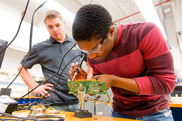 Ryan Dixon helps Howard Williams solder a circuit board