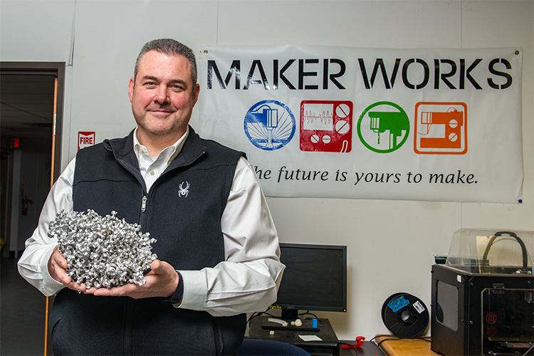 Tom Root with a cast aluminum sculpture at Maker Works