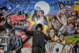 Marsha Battle Philpot pointing out her father's record store and her father in Curtis Lewis' mural at Bert's Warehouse Theatre