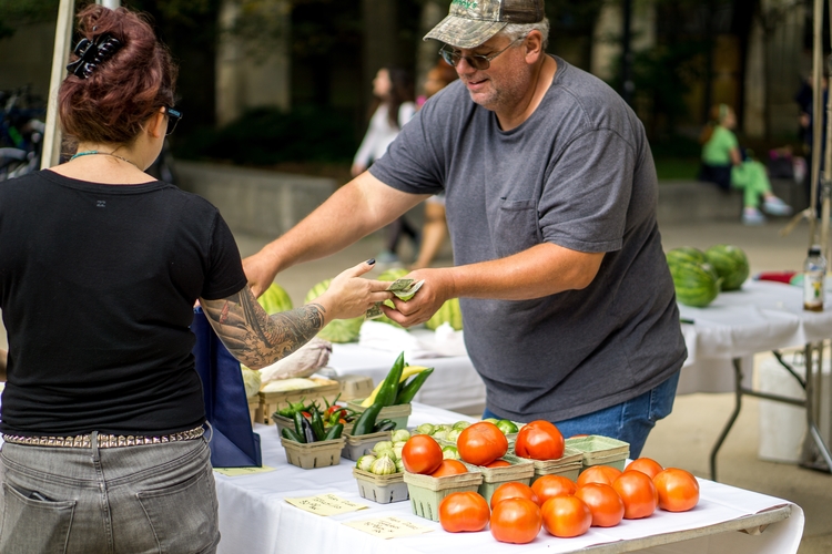 A farmer sells produce at an M Farmers Market.