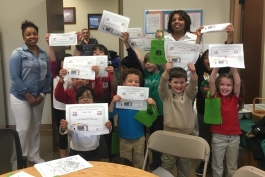 Young participants in Joyful Treats' Cooking Academy hold up their graduation certificates.