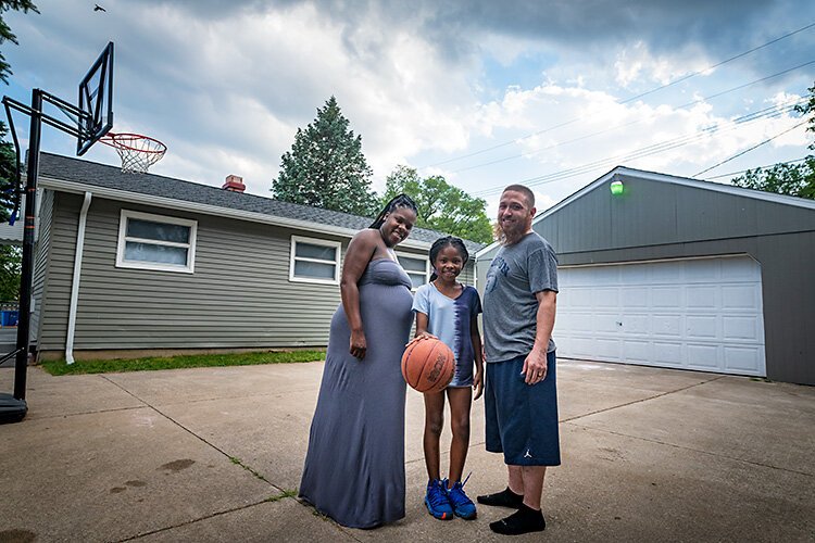 Adriya Perry, her daughter Akavayia, and husband Phil outside their new home in Ypsilanti Township.