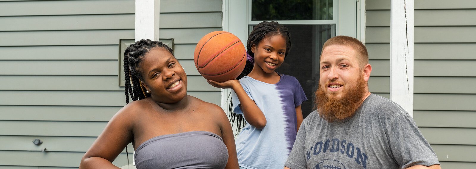 Adriya Perry, her daughter Akavayia, and husband Phil outside their new home in Ypsilanti Township.