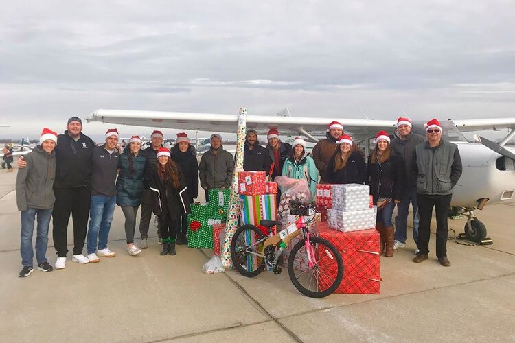 EMU volunteers with one of the planes they used to deliver presents for Operation Good Cheer.