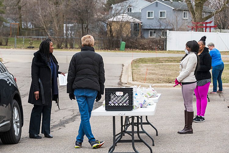 Alena Zachery-Ross talks to volunteers handing out lunches at Christian Love Church.