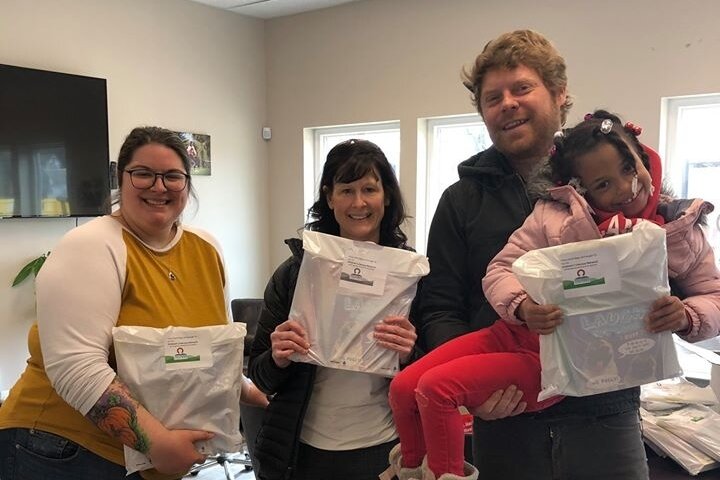 CLN and CAN staff (including executive director Betsy Durant, center) hold up literacy bags.