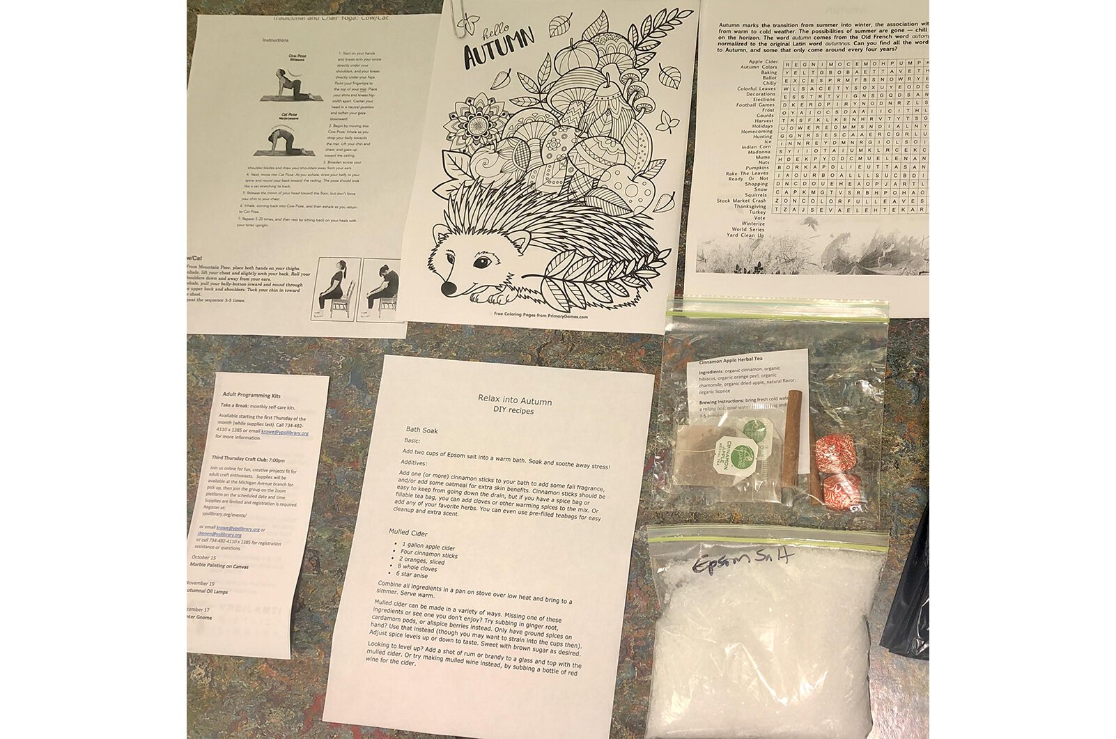 October's apple-themed self-care kit included cinnamon sticks, spiced apple tea, crossword pages, chocolates, recipes, a breathing exercise, and instructions for a yoga pose. 