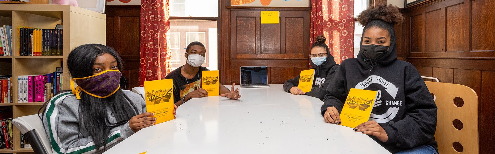 Educate Youth student participants hold up copies of "Spiritual Warriors," a book featuring their poetry.