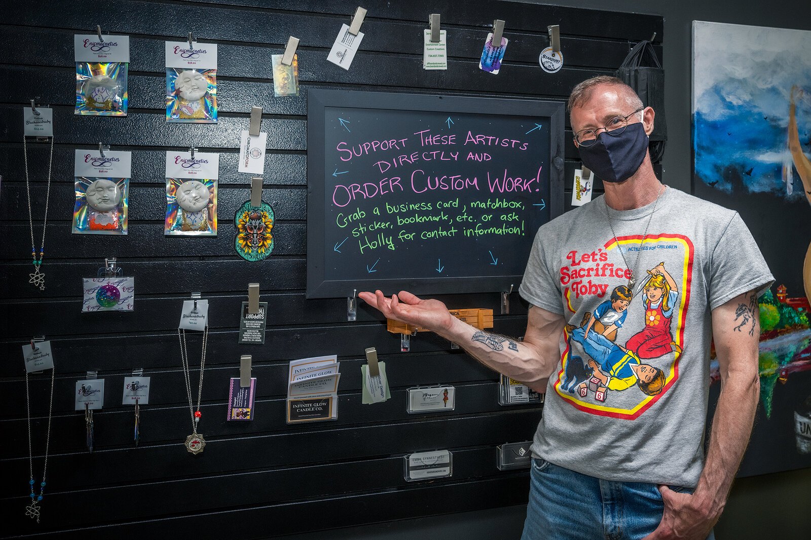 Ypsilanti author Ken MacGregor in front of the wall of local artists' business cards at Stardust.