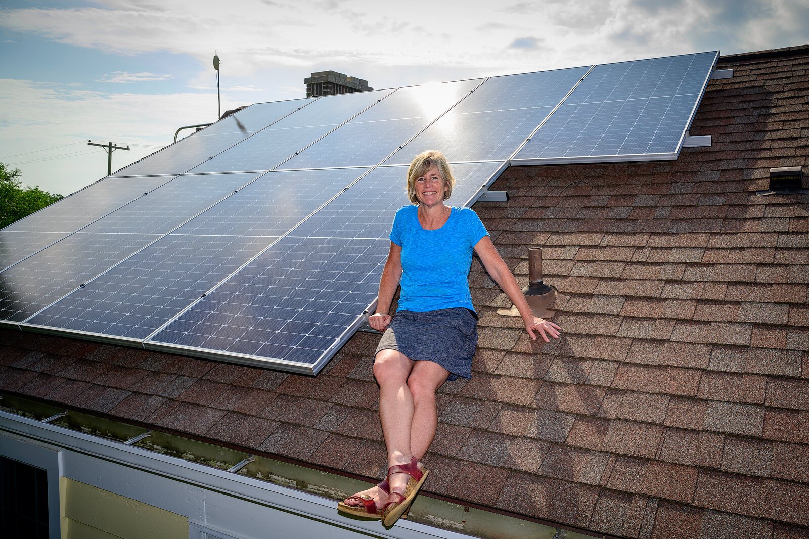 Growing Hope Executive Director Cynthia VanRenterghem sits next to the solar panels installed at Growing Hope in Ypsilanti, which were funded by a grant from the Solar Moonshot Program. 