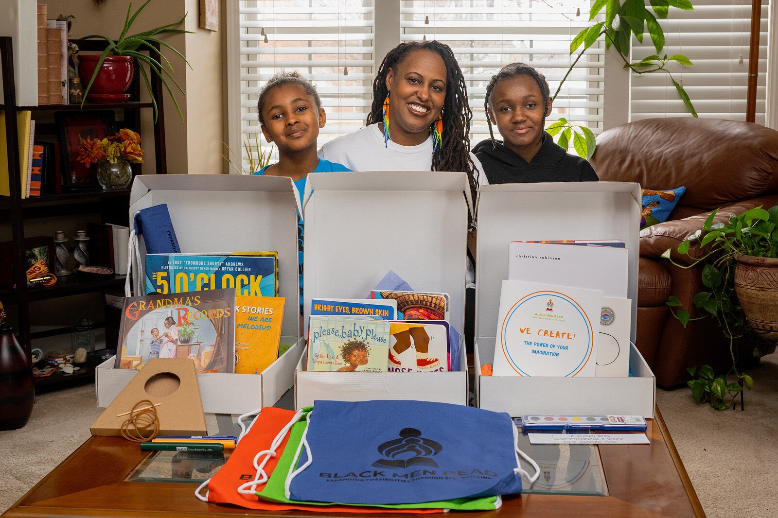 Zuri Ibarisha, Tamara Tucker-Ibarisha, and Aya Ibarisha check out the Black Men Read subscription book boxes.