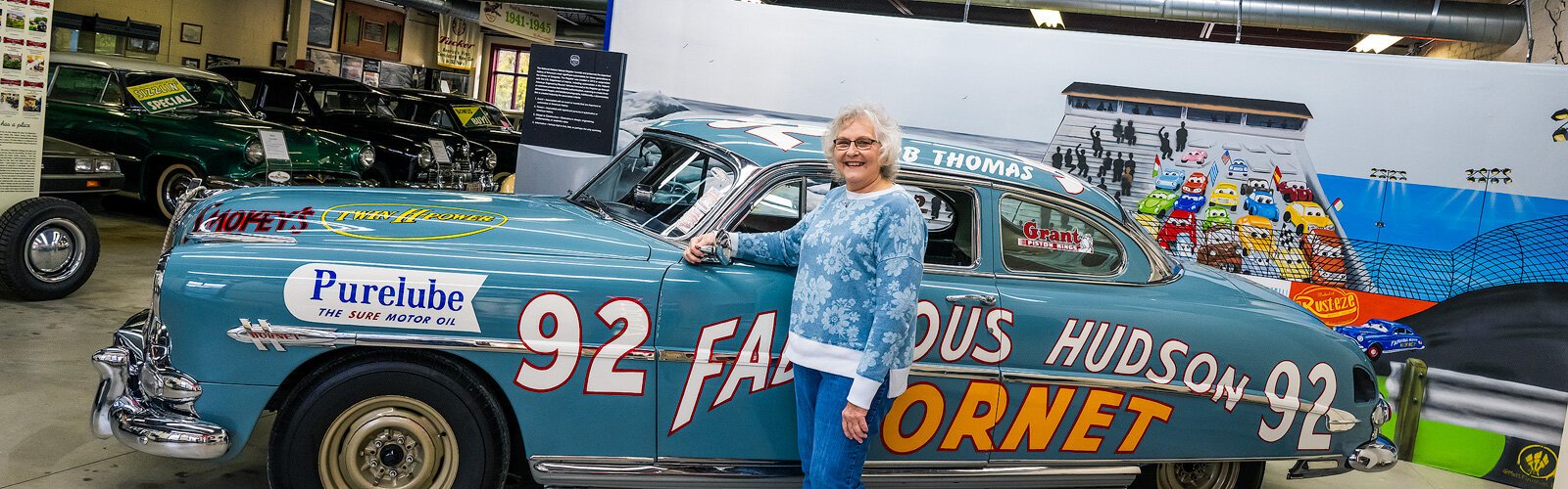 Patti Bluhm with the 1952 Hudson Hornet racing car at The Ypsilanti Automotive Heritage Museum.