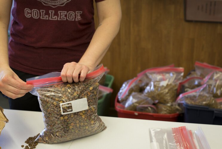 A volunteer for the Humane Animal Treatment Society (HATS) assembles packages of cat and dog food for distribution at the William and Janet Strickler Nonprofit Center to provide food assistance to those in need.