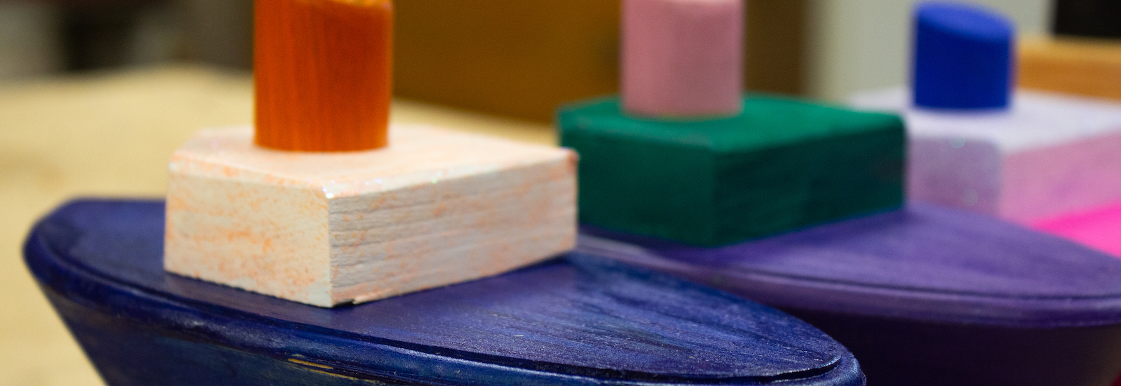 Wooden tug boats are painted brightly before being donated to charity.