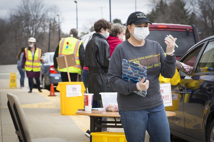 : Staff and volunteers work outside of the William and Janet Strickler Nonprofit Center to distribute food and emergency hygiene kits to those in need.