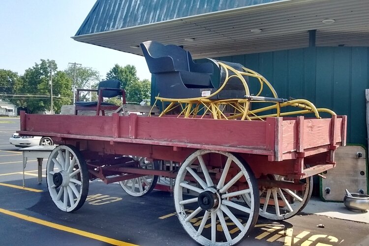 This freight wagon and sleigh are horse drawn vehicles from the late 19th century.  These and other large items are displayed outdoors in front of Antiques and Uniques.