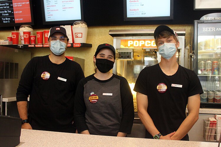 Celebration Cinema staff members Jacob Helm (left), Bella Melendez, and Brody Gibas (right), sport their game day pins at work.