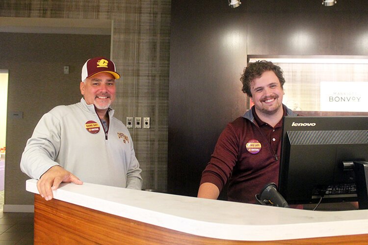 Courtyard Marriott General Manager, Scott Schurr (left), and employee Patrick Kemmerling pose for a photo wearing their game day pins.