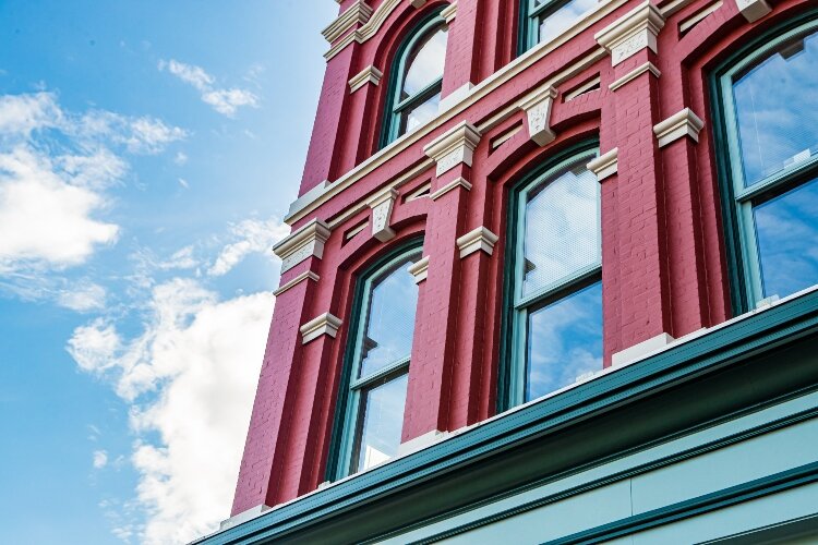 In the Commercial Italianate style, the windows on the second and third floors are evenly placed among brick masonry columns. 