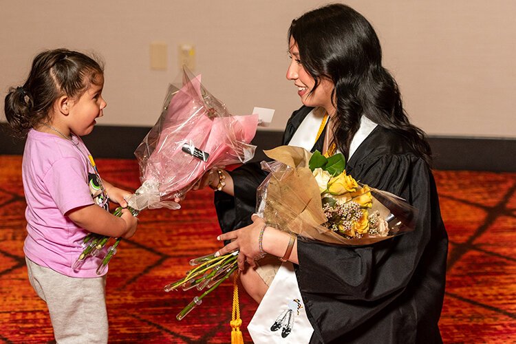 SCTC graduate receives flowers from a young girl after the commencement ceremony.