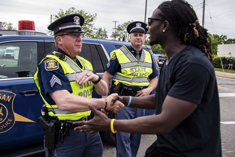 Trokon Jayqua, right, thanks police officers during a march to protest the death of George Floyd and social injustice June 1 on Mission Street in Mount Pleasant, MI.