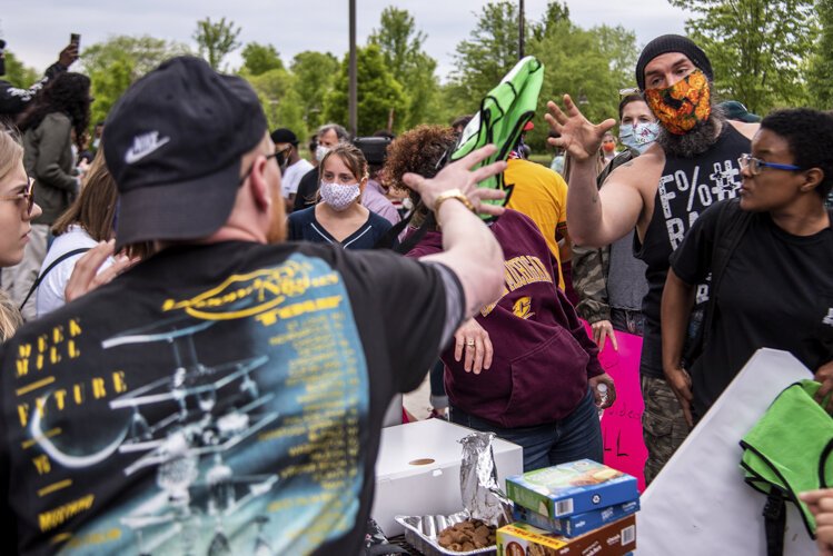 Organizer Steven Green throws a vest to John Campbell, who volunteered as a peace moderator for an event to protest the death of George Floyd and social injustice June 1 outside the Bovee University Center in Mount Pleasant, MI.