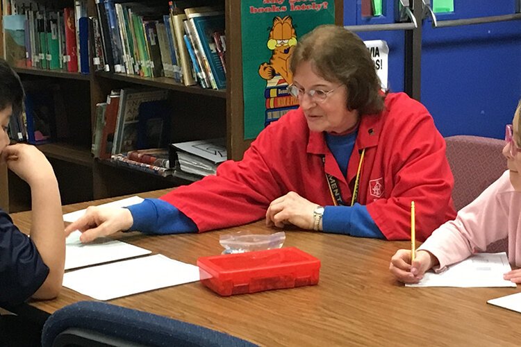 A foster grandma works with students at a local school. 