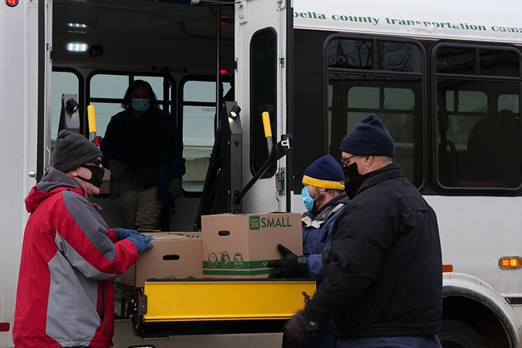 Volunteers load packages from The Care Store onto I-Ride buses so they can be delivered.