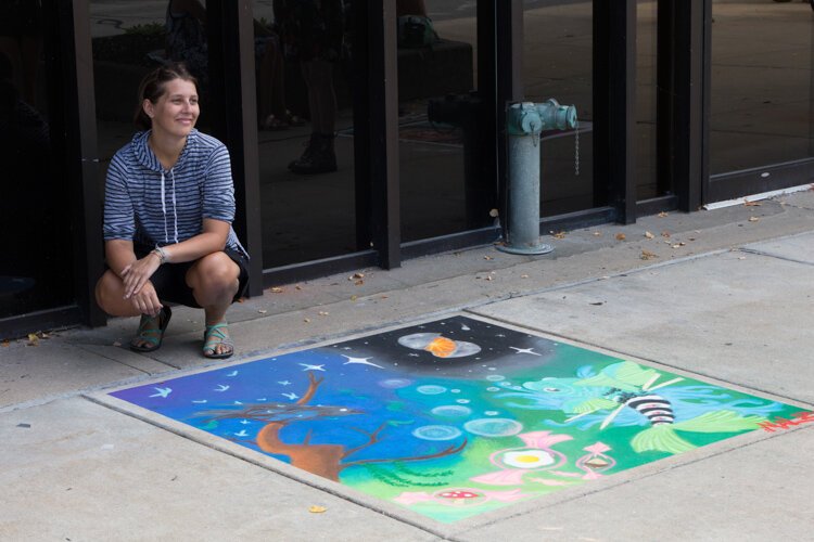 First place Chalk the Walk winner Malia Reger poses with her artwork. "I just kind of started drawing," she says. "I did a sketch of it and I drew the fish first and then I just kind of kept with the surrealism and just kind of built it from there."