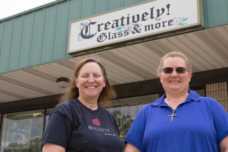 Owner Jean Holland (right) and her employee Sharon Holzhausen pose for a photo outside Creatively! Glass & More.