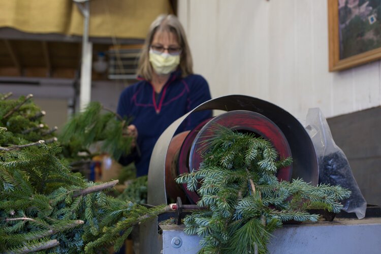 Vander Sys Tree Farm Nursery owner Laura Allen uses a machine to make garland from leftover branches.