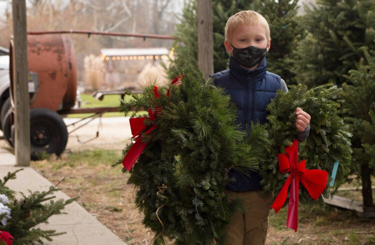 Logan Rudy, 7, holds two of the three wreaths his family purchased from Vander Sys Tree Farm Nursery. One wreath is for his grandmother and the other for their chicken coop.