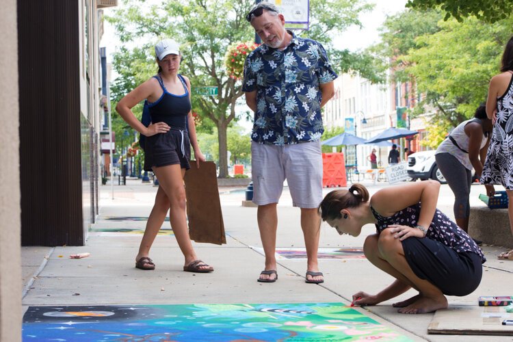 Chalk the Walk artists and family members admire other artworks while they wait for the judges.