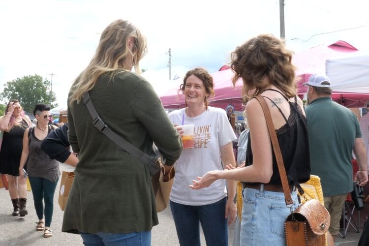 Alongside shoppers, Lacey Badelt (center) with fresh lemonade from vendor Little Lemon at the 2024 “Small Town USA Market.”