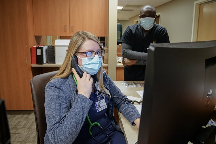 Robyn Sabol, R.N., at MidMichigan Health, sets up a telemedicine visit with a patient while Dr. Utibe Effiong looks on.
