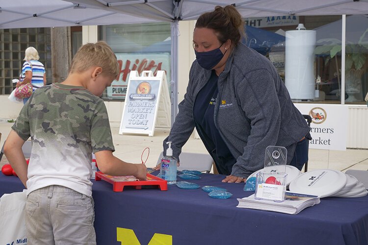 Ashley Brenner, Community Health Supervisor for MidMichigan Medical Centers – Mt. Pleasant, Gratiot, and Clare, volunteers during the Harrison Street Fair and talks with a young boy playing “Operation” at MidMichigan Health’s booth.