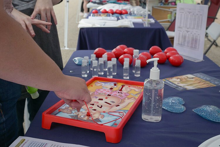 Kids play “Operation” at MidMichigan Health’s booth during the Harrison Street Fair.