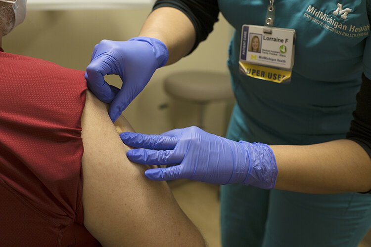 A bandage is applied to a patient who received Pfizer's COVID-19 vaccine at the  MidMichigan Medical Center - Mt. Pleasant on Saturday, Jan. 16, 2020.  