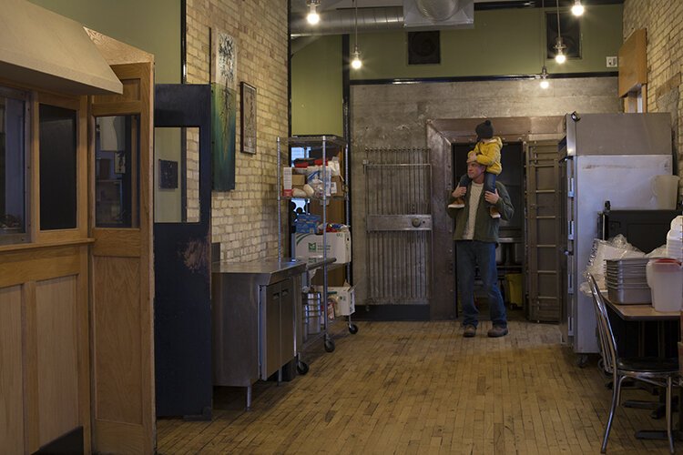 Owner Chris Bair and his 3-year-old son Roman walk around in the dining room of Roz's Diner, which had a 27-chair capacity before the restaurant ended service in October. 