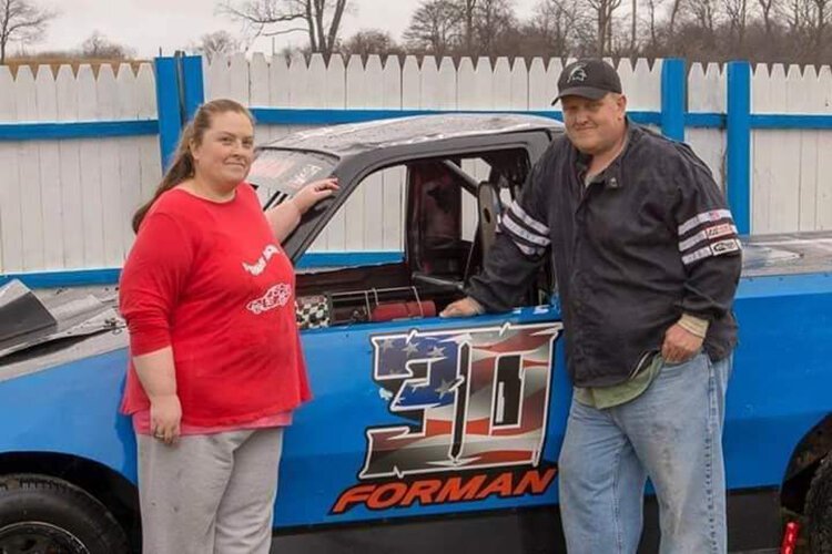 Shane Forman poses with his wife, Regina Forman, in front of his race car.