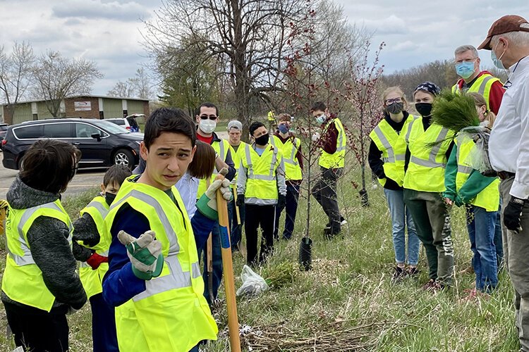 Spencer Melton, a member of the Boy Scout of America Troop 604B, instructs the group of volunteers on how to properly plant trees. 