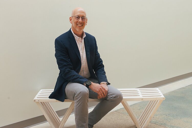 Chief Development Officer Marc Berke sitting on a bench in the new Grand Rapids office space.