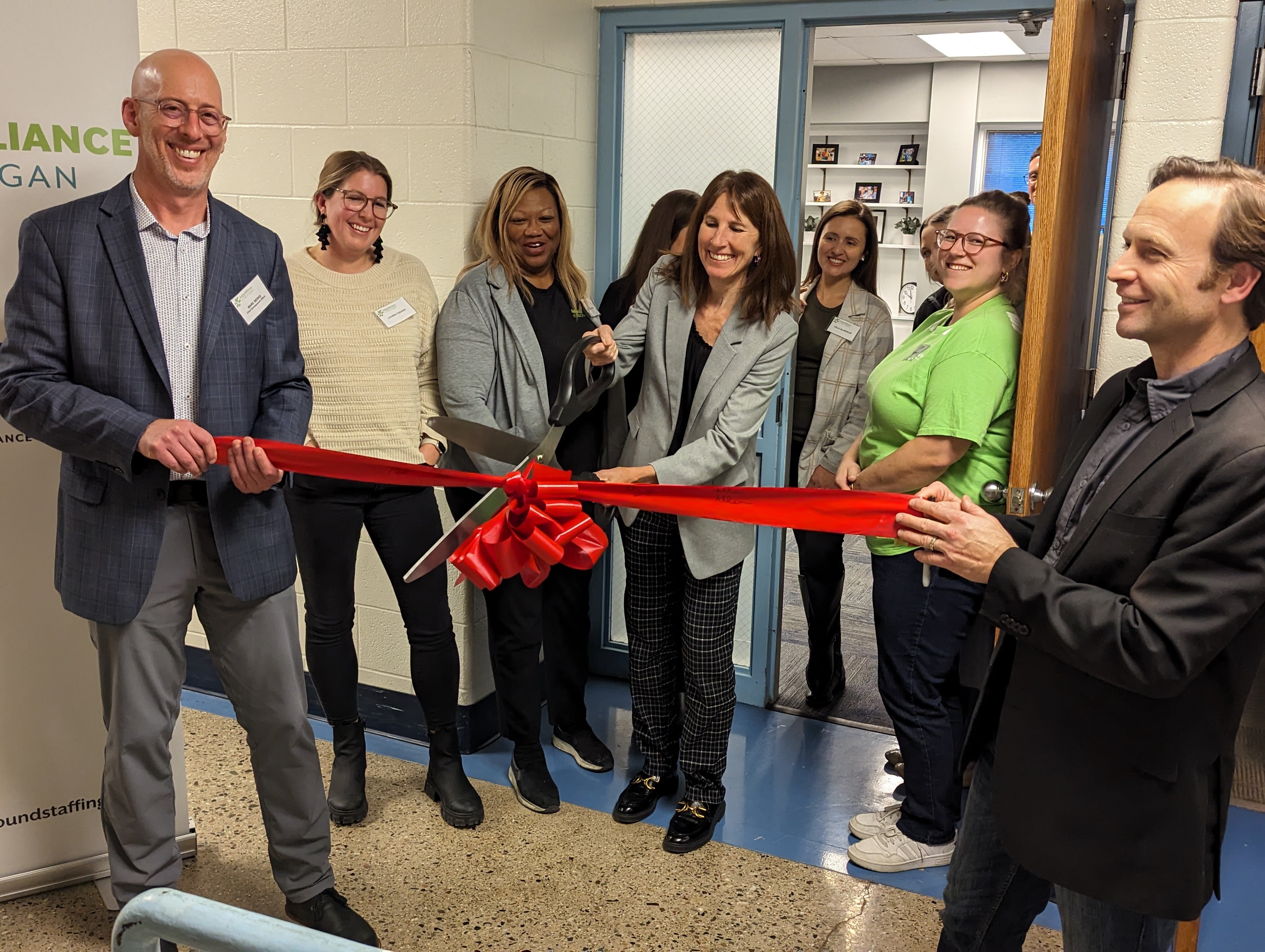 The CEO Colleen Allen cuts the ribbon to the new office alongside other AAoM staff members to celebrate the grand opening of AAoM's Grand Rapids office.