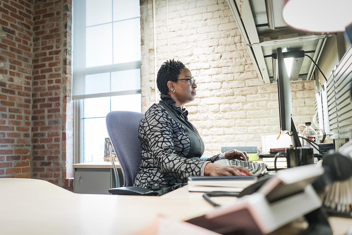 Flint, MI - Thursday, November 2, 2017: Detroit resident Denise Smith, 55, sits at her office desk in the Community Foundation Building addressing emails and taking care of tasks for the day. Smith, the Executive Director for the Flint Early Childhoo